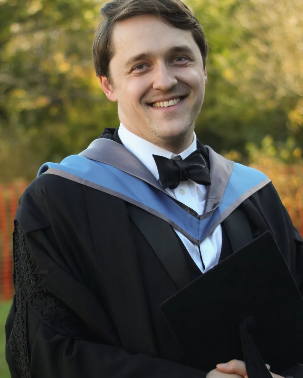 Vasilii in his Oxford graduation gown, with autumn trees behind him.